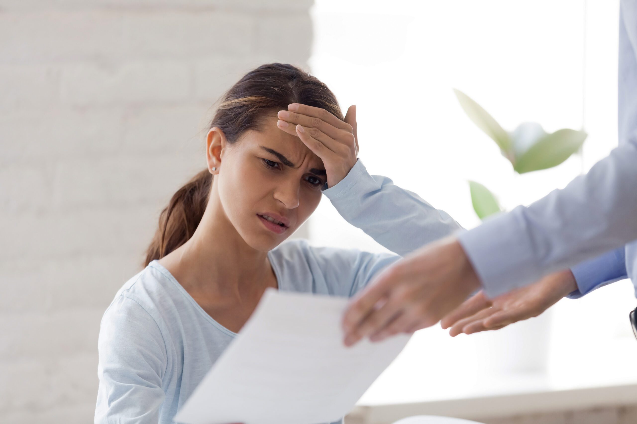 Frustrated person sitting at desk surrounded by scattered immigration documents and forms with confused expression indicating visa application difficulties
