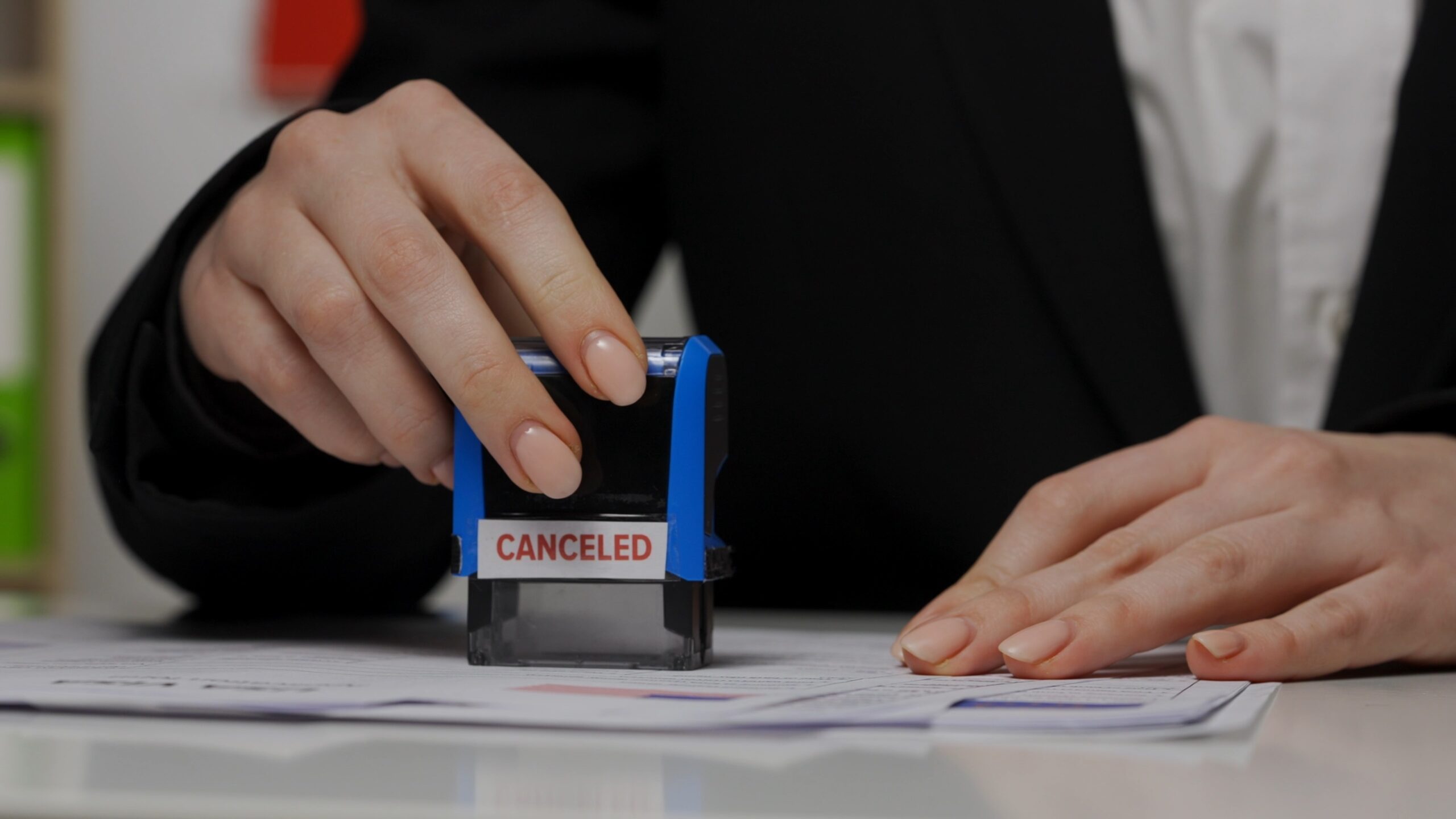 Frustrated person sitting at desk surrounded by scattered immigration documents and forms with confused expression indicating visa application difficulties