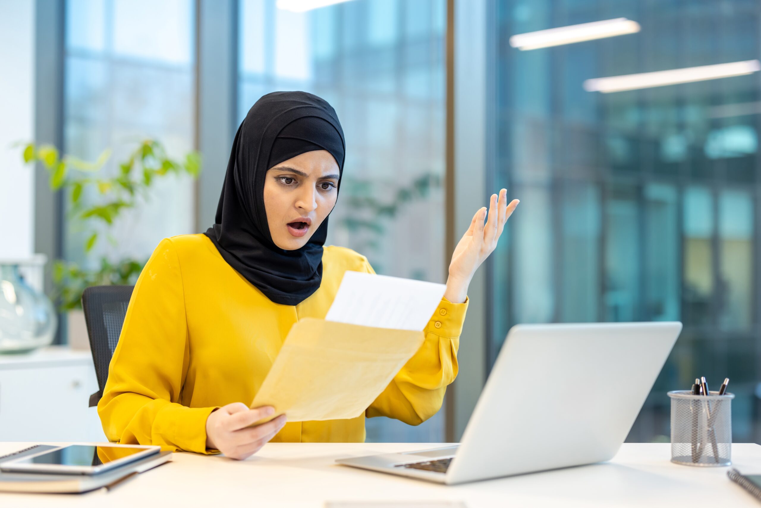 Frustrated person sitting at desk surrounded by scattered immigration documents and forms with confused expression indicating visa application difficulties